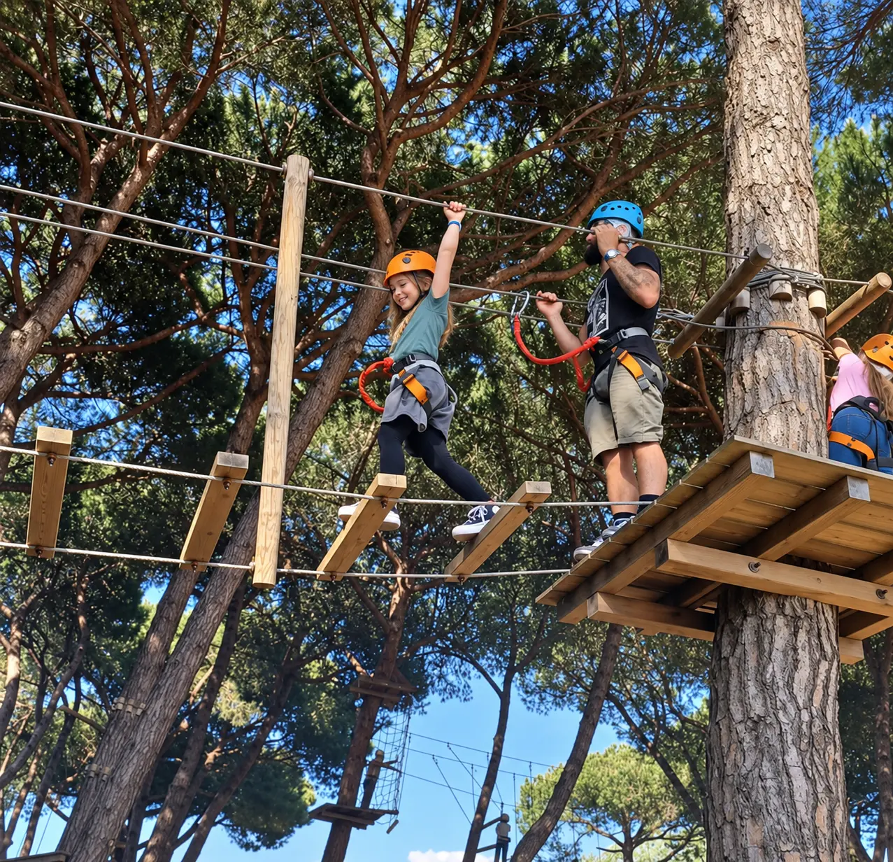 Un gruppo di amici e famiglie con casco si dà il cinque tra i pini
